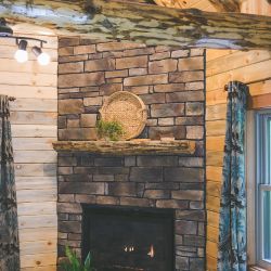 Gas Fireplace Covered with Stone Veneer and Topped with a Log Mantle