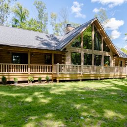 Ranch Log Home with Shingle Roof and Large Trapezoid Windows